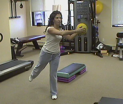 A woman in the gym throwing a frisbee.