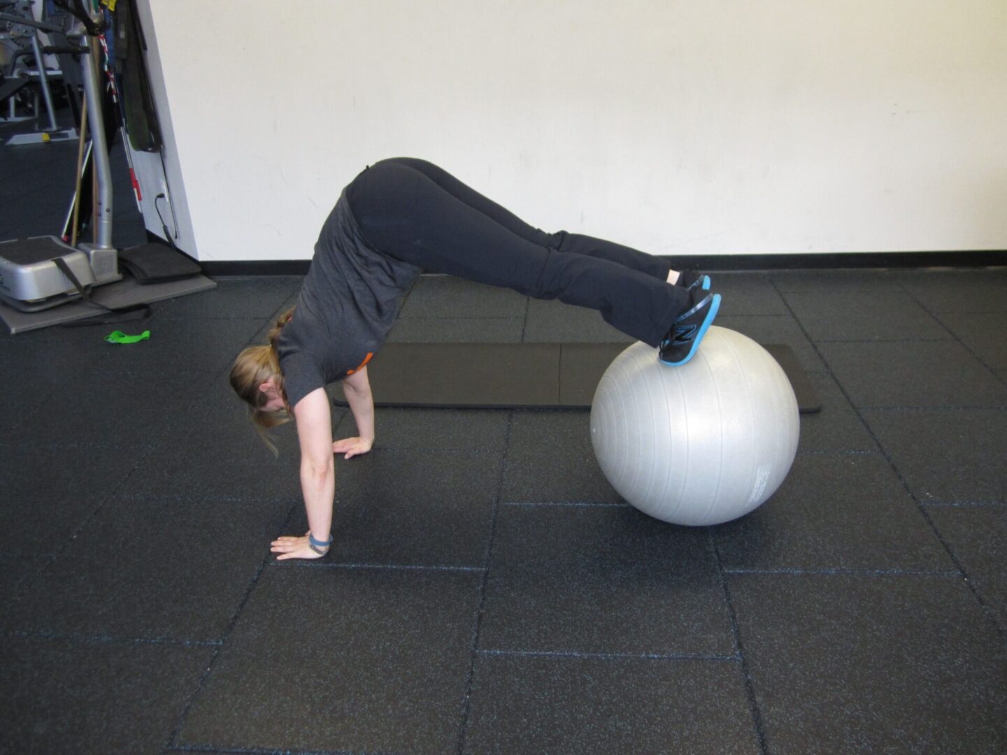 A woman is doing a handstand on an exercise ball.
