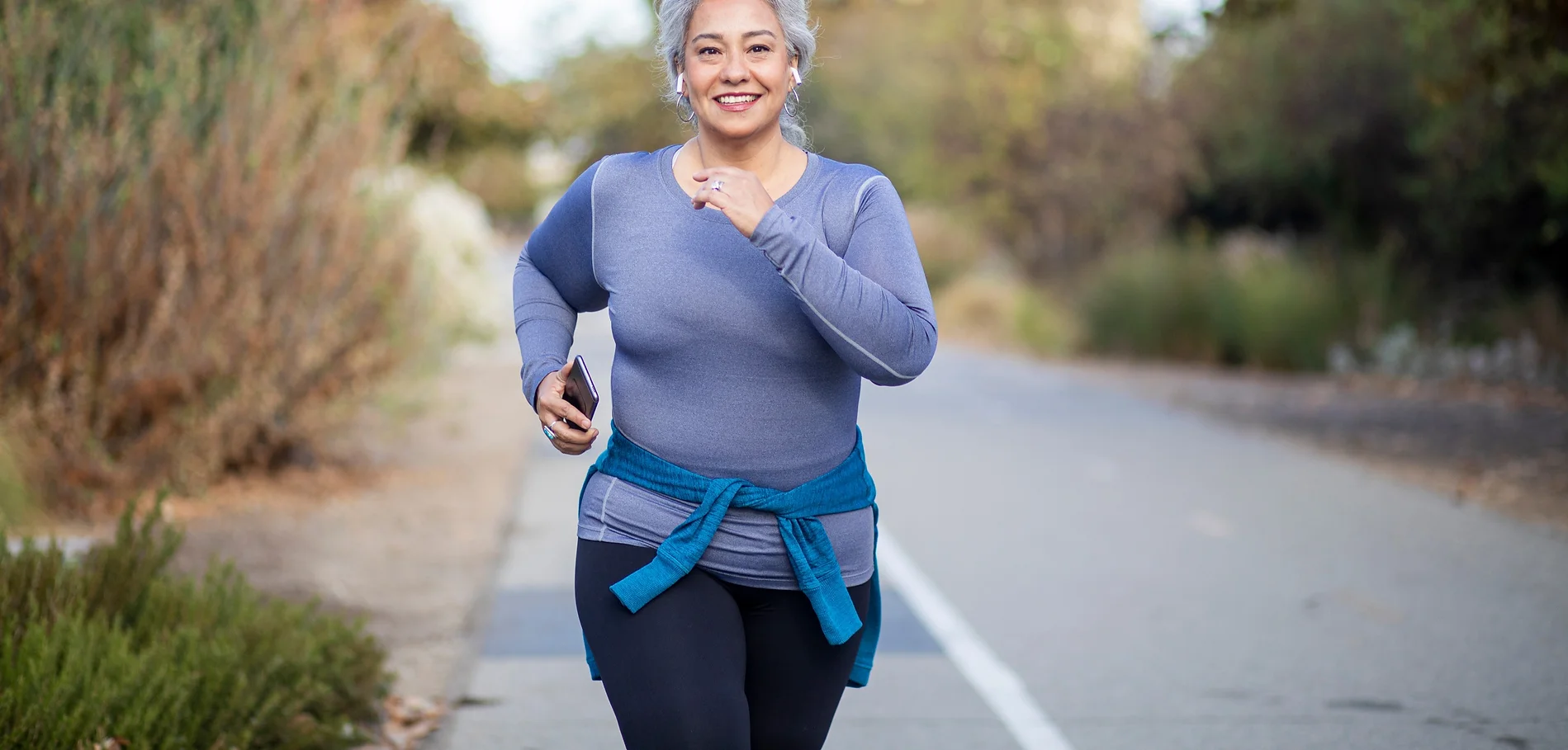 A woman is running on the street with her phone.