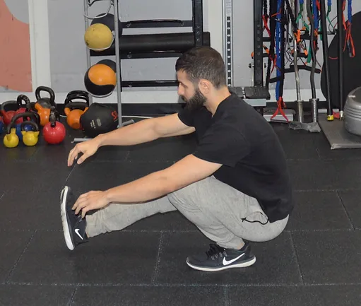 A man squatting on the ground in front of several other people.