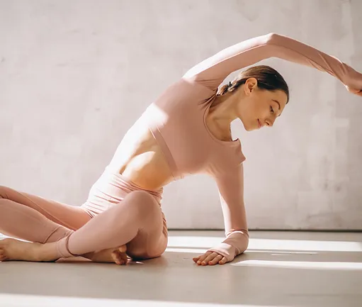 A woman in pink is doing yoga on the floor