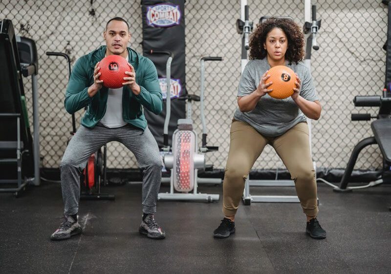Two people squatting with balls in their hands.