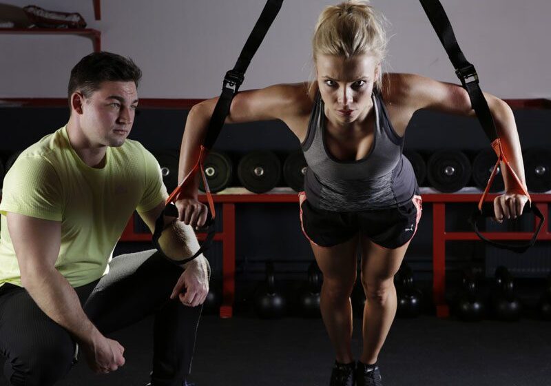 A woman is doing some exercises with a trainer.